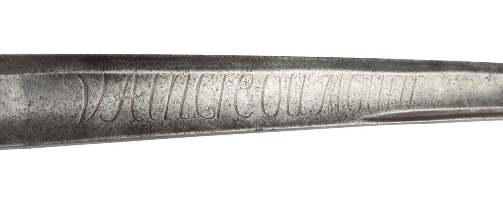 Close-up view of a vintage sword blade featuring intricate engraved lettering.
