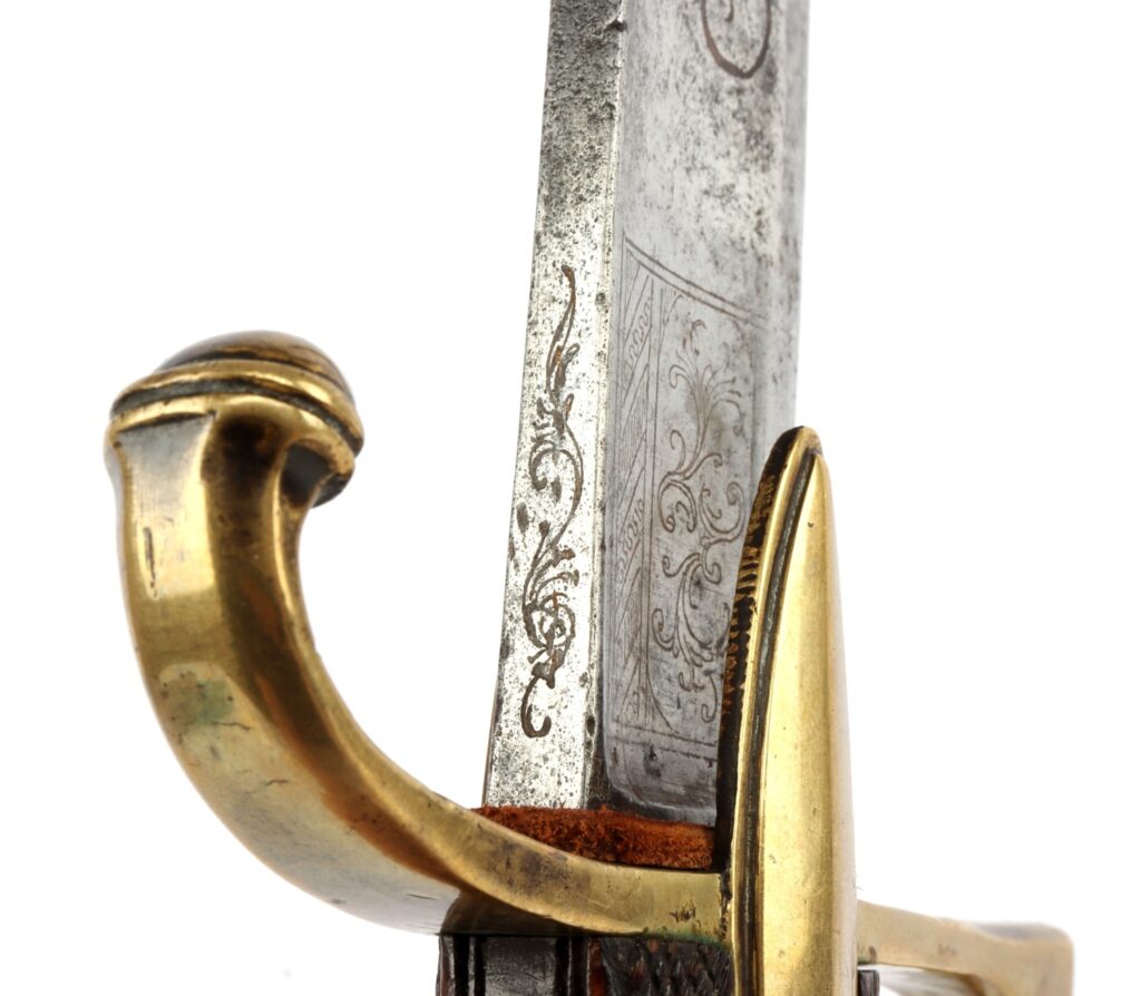 Close-up of a decorative sword blade featuring ornate engravings and a brass hilt.