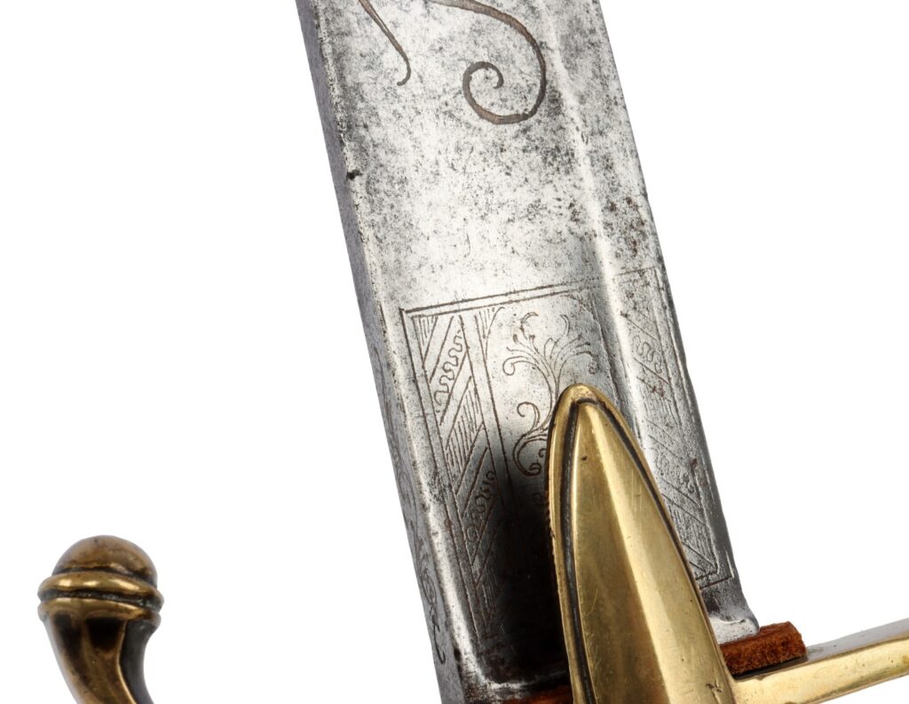 Close-up of an ornate sword blade with intricate engravings and a golden hilt.