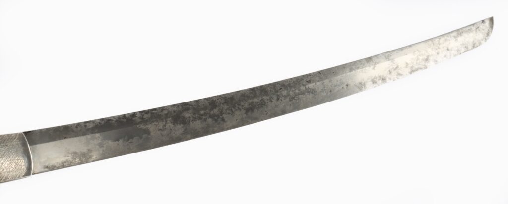 A close-up view of a curved sword blade with a polished finish and textured surface.