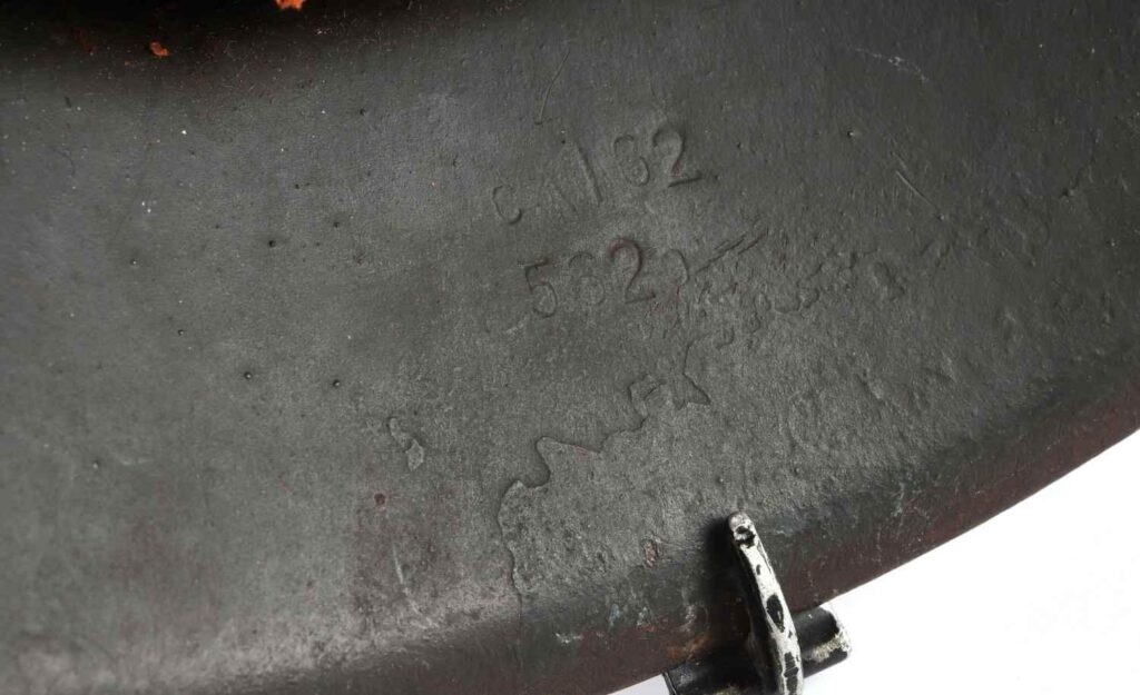 Close-up of a textured metal surface displaying engraved markings and numbers.